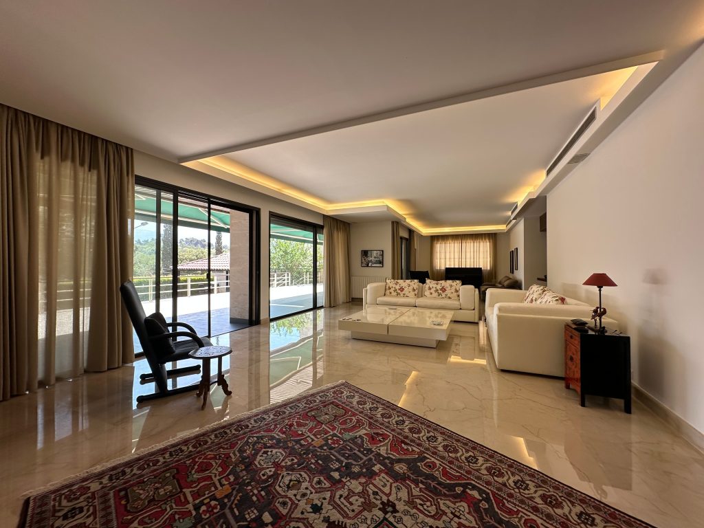 Elegant and spacious living room with modern decor, overlooking a scenic outdoor area through large windows.
